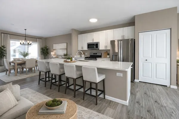 a kitchen with stainless steel appliances a dining table chairs refrigerator and sink