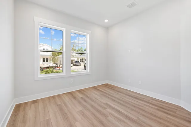 an empty room with wooden floor and windows