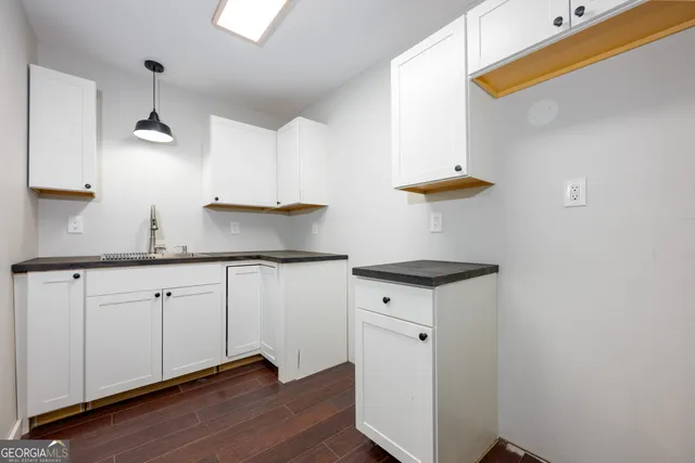 a kitchen with granite countertop a sink cabinets and wooden floor