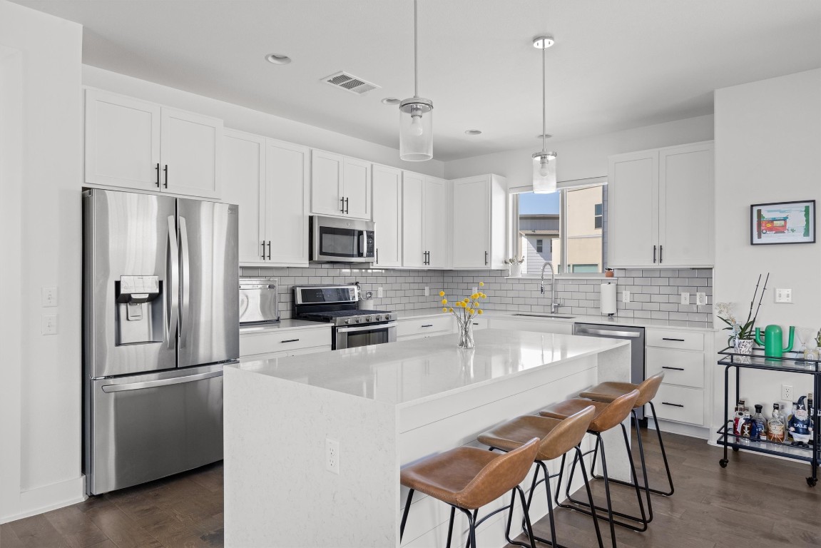 5315 La Crosse Avenue, Unit 18 Austin, TX 78739 - Photo 13 of 40 Kitchen with stainless steel appliances, a kitchen bar, a center island, light stone countertops, and white cabinets