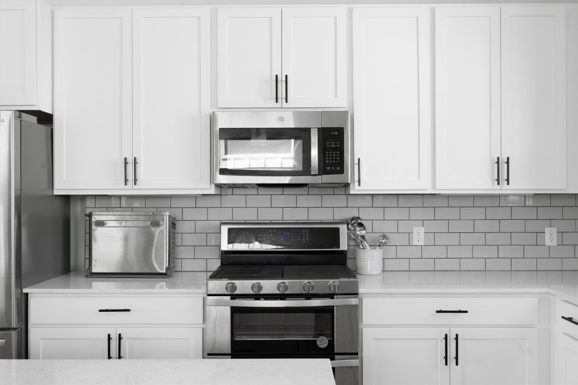 5315 La Crosse Avenue, Unit 18 Austin, TX 78739 - Photo 16 of 40 Kitchen with white cabinets, appliances with stainless steel finishes, tasteful backsplash, and light stone counters