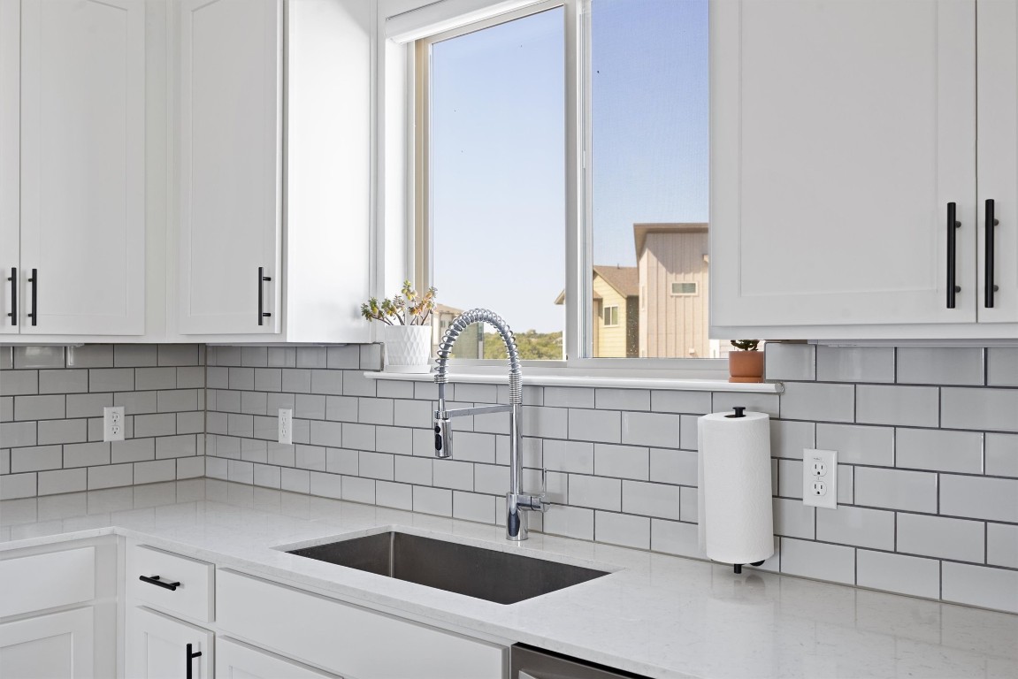 5315 La Crosse Avenue, Unit 18 Austin, TX 78739 - Photo 20 of 40 Kitchen featuring light stone counters, white cabinets, and decorative backsplash