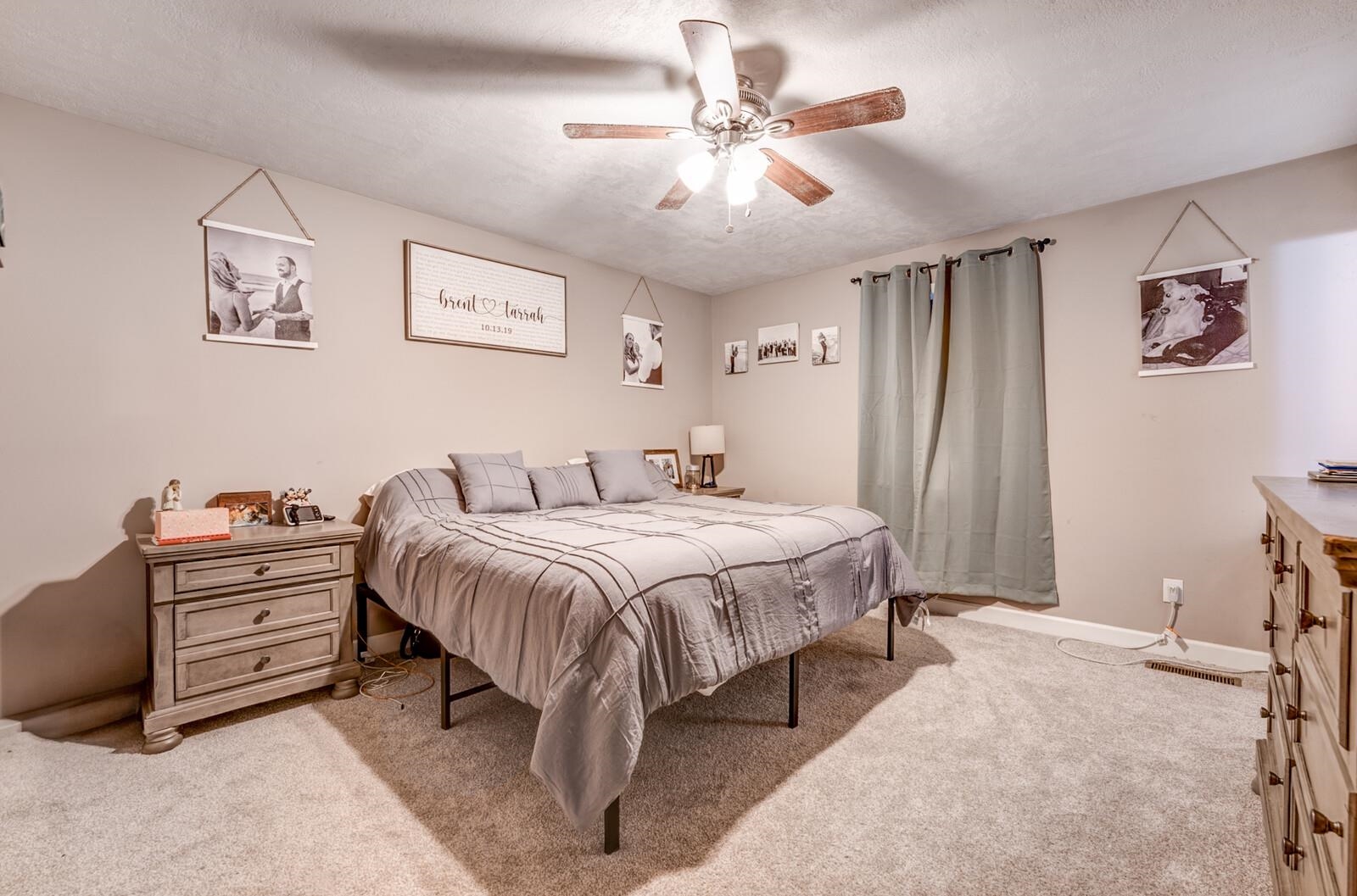 10 Raphael Cove Munford, TN 38058 - Photo 12 of 23 a spacious bedroom with a bed and a chandelier