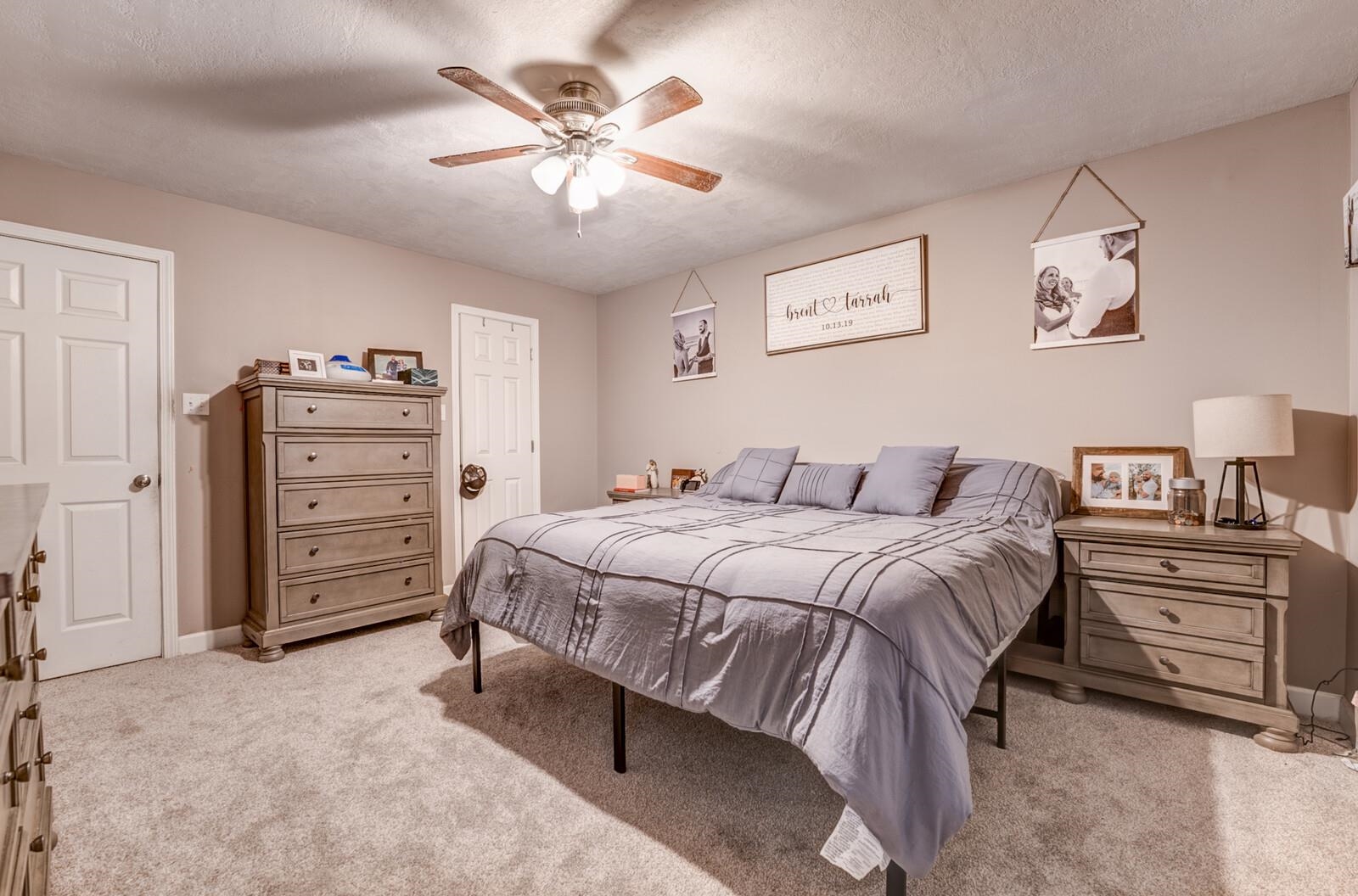 10 Raphael Cove Munford, TN 38058 - Photo 13 of 23 a spacious bedroom with a bed and a chandelier
