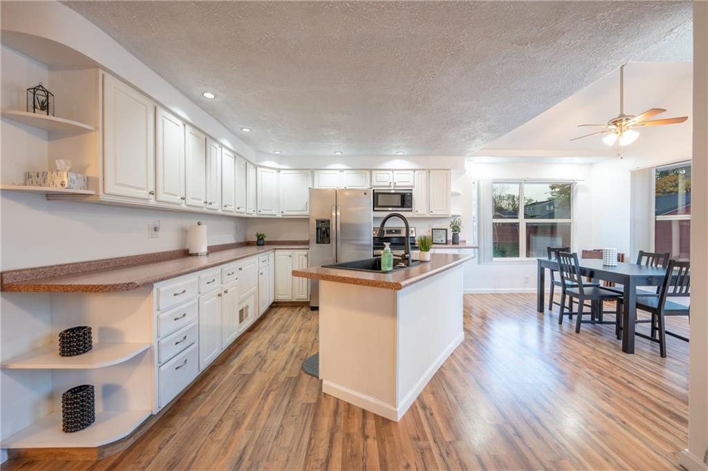 136 Long Drive Irwin, PA 15642 - Photo 10 of 50 a kitchen with stainless steel appliances granite countertop wooden floors a stove and white cabinets
