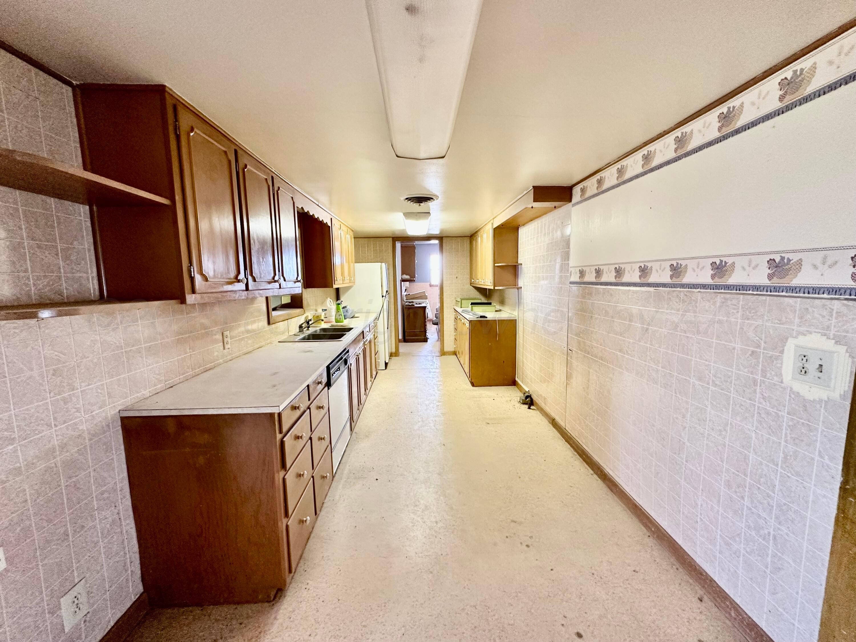 6675 Highway 86 Tulia, TX 79088 - Photo 64 of 68 a kitchen with stainless steel appliances granite countertop a refrigerator a sink dishwasher a stove and a dining table with wooden floor
