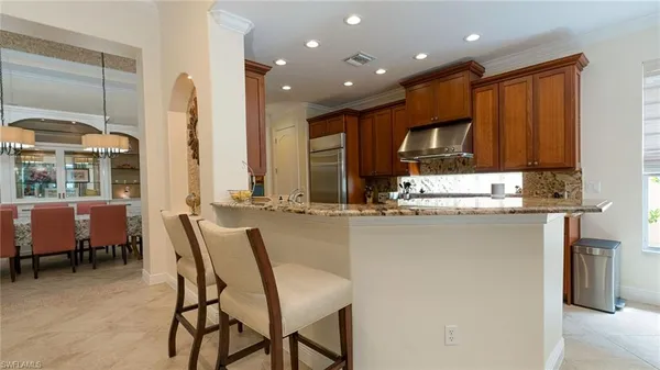 a kitchen with kitchen island granite countertop wooden cabinets and a refrigerator