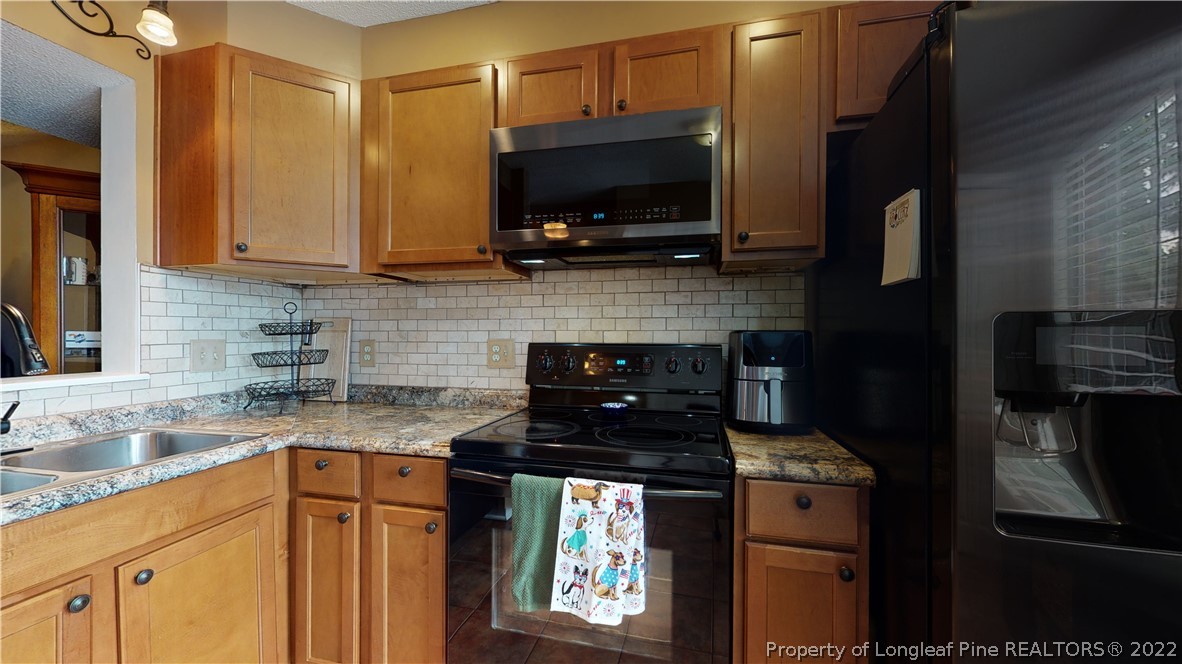4604 Pine Trace Drive Raleigh, NC 27613 - Photo 5 of 30 a kitchen with stainless steel appliances granite countertop a stove microwave and refrigerator