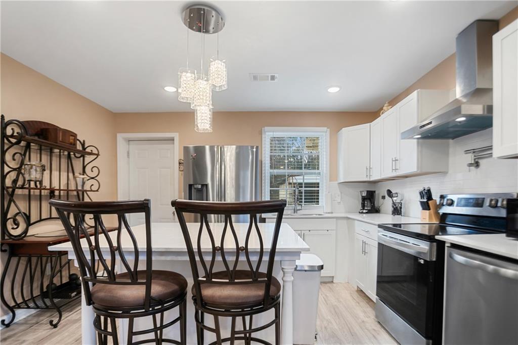142 Hutton Place Northwest Atlanta, GA 30318 - Photo 4 of 14 a kitchen with stainless steel appliances granite countertop a stove a sink dishwasher a dining table and chairs with wooden floor