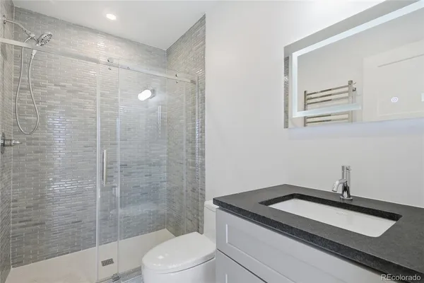 a bathroom with a granite countertop sink a toilet and shower