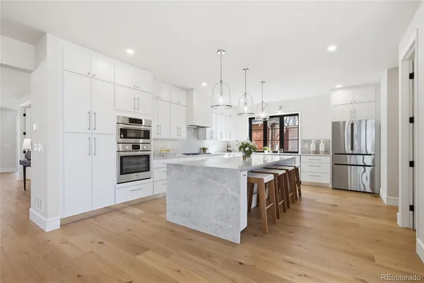 a large kitchen with stainless steel appliances kitchen island granite countertop a refrigerator and a stove top oven