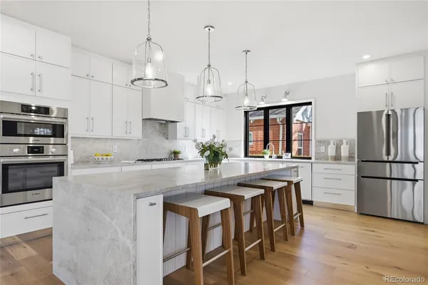 a kitchen with stainless steel appliances granite countertop a table chairs refrigerator and microwave