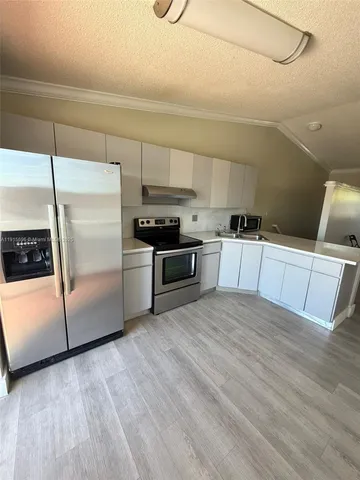 a kitchen with stainless steel appliances a refrigerator a sink and white cabinets
