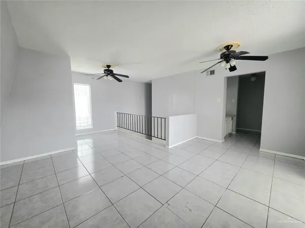 a view of an empty room and chandelier fan