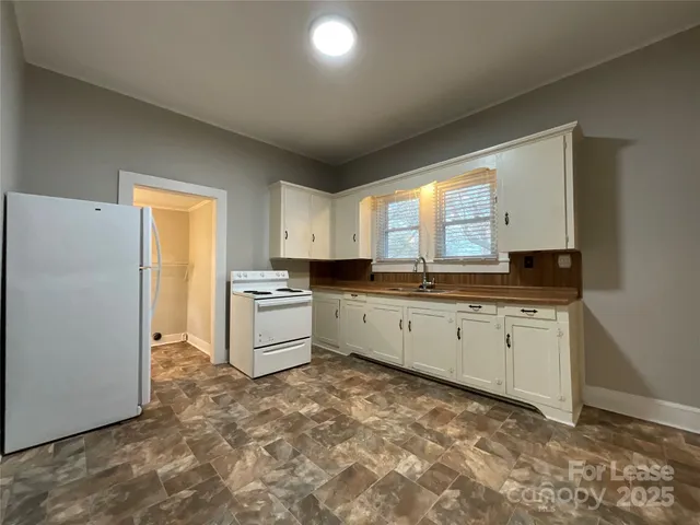 a large white kitchen with a stove a refrigerator and a sink