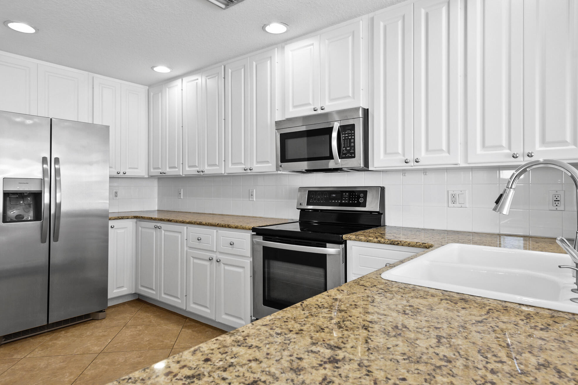 1836 Jeaga Drive Jupiter, FL 33458 - Photo 3 of 25 a kitchen with stainless steel appliances granite countertop a stove a sink and a microwave