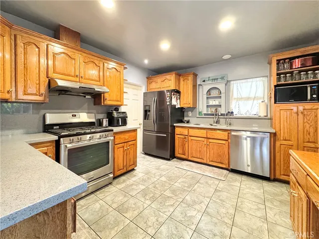 a kitchen with stainless steel appliances granite countertop a stove a sink and a refrigerator
