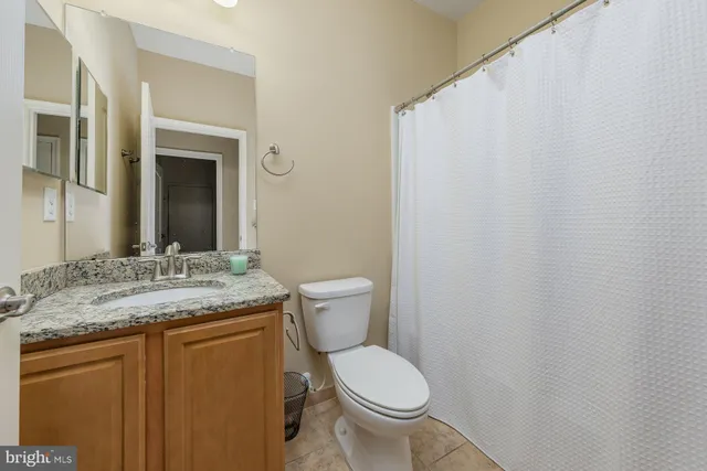 a bathroom with a granite countertop sink toilet and mirror