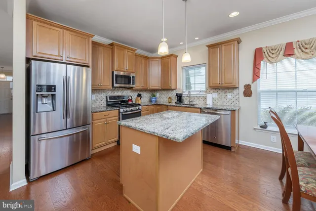 a kitchen with stainless steel appliances granite countertop a refrigerator a stove a sink a dining table and chairs