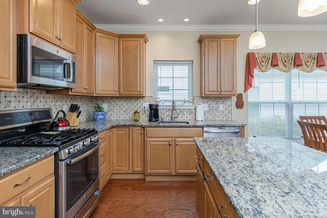 a kitchen with granite countertop a sink a stove and cabinets
