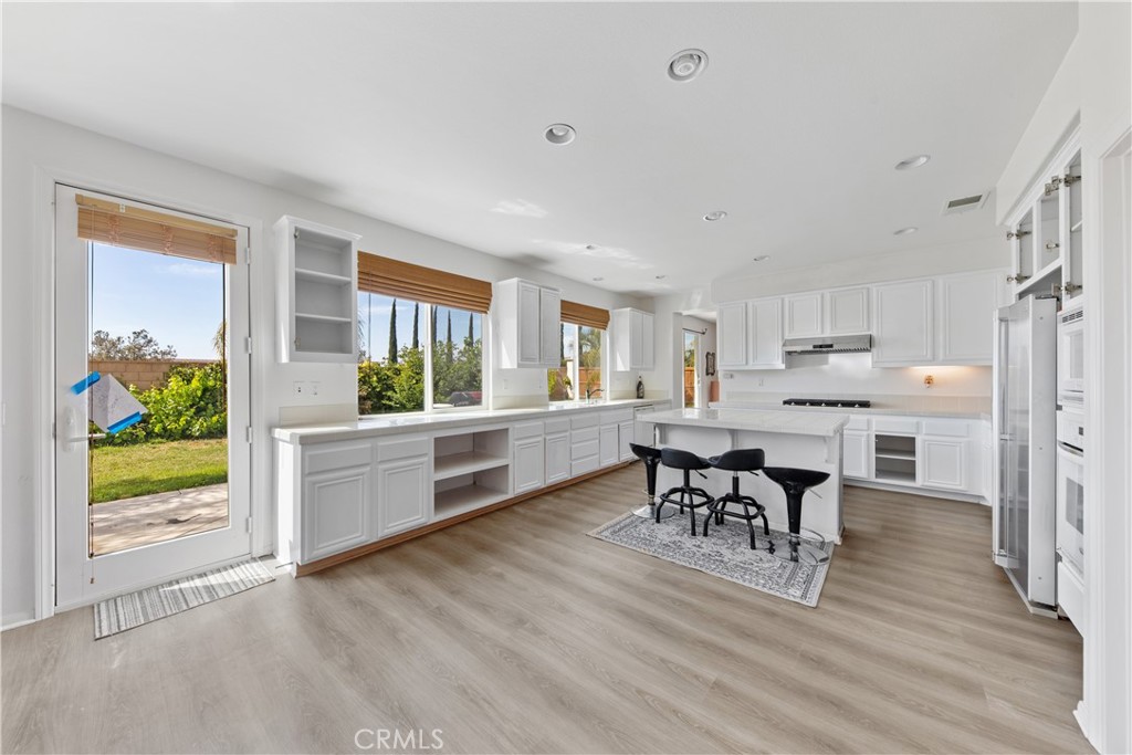 a kitchen with stainless steel appliances a dining table chairs and wooden floor