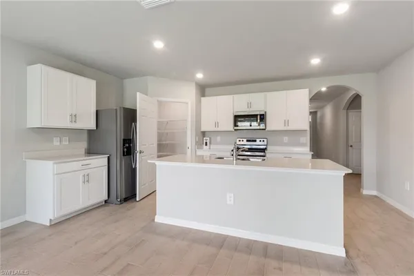 a large kitchen with stainless steel appliances a refrigerator a stove top oven a sink and dishwasher