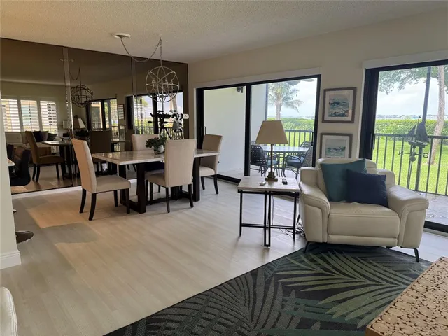 a living room with furniture two large windows and a table