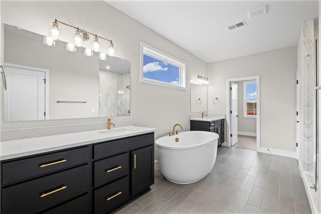 714 Conley Drive Canton, GA 30115 - Photo 25 of 51 a spacious bathroom with a double vanity sink a mirror and a bathtub