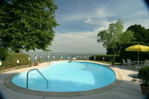 Undisclosed Address Darien, CT 06820 - Photo 4 of 8 a view of a swimming pool with lawn chairs under an umbrella