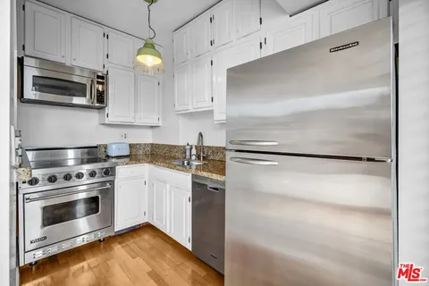 a kitchen with cabinets stainless steel appliances and wooden floor