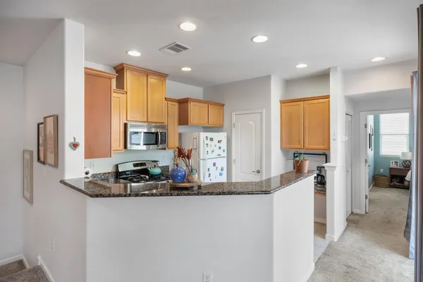 a kitchen with kitchen island granite countertop a refrigerator and a sink