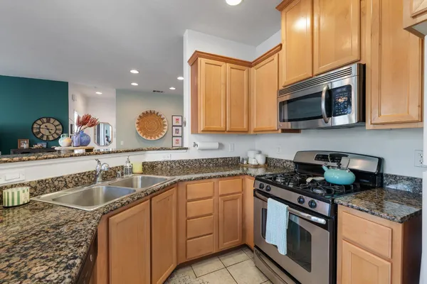 a kitchen with granite countertop a sink stove and microwave