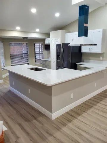 a large kitchen with stainless steel appliances a large counter top and a wooden floors