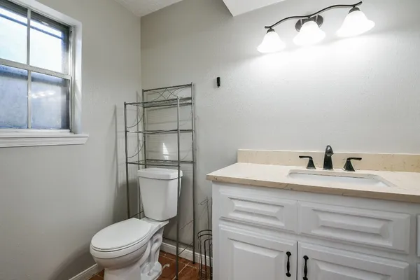 a bathroom with a granite countertop toilet sink and mirror