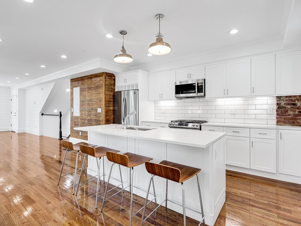 30 Copeland Street, Unit 1 Boston, MA 02119 - Photo 15 of 40 a kitchen with stainless steel appliances granite countertop a stove top oven a sink dishwasher and a refrigerator with wooden floor