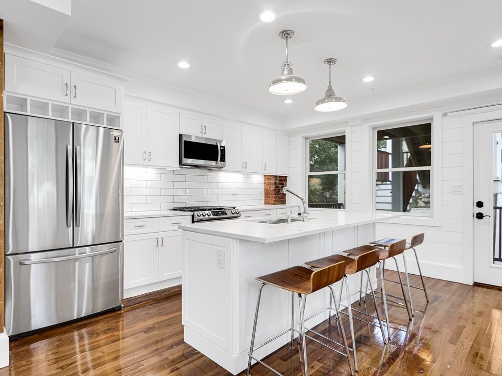 30 Copeland Street, Unit 1 Boston, MA 02119 - Photo 9 of 40 a kitchen with stainless steel appliances a stove a refrigerator a sink dishwasher and a refrigerator with wooden floor