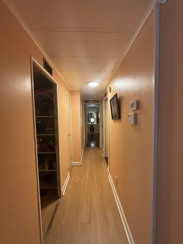 a view of a hallway with wooden floor and closet