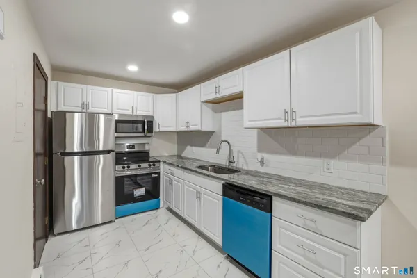 a kitchen with stainless steel appliances granite countertop a refrigerator sink and stove