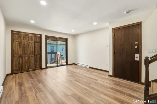 a view of an empty room with wooden floor and a window