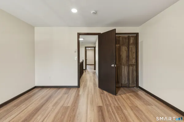 a view of a hallway with wooden floor and a bathroom