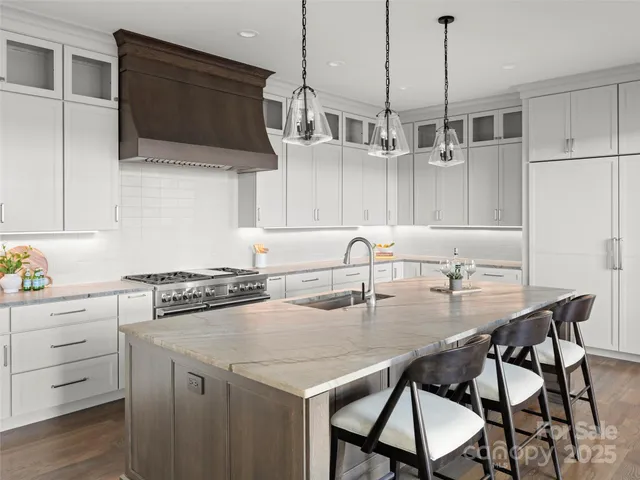 a kitchen with stainless steel appliances granite countertop a stove a sink a microwave a dining table and chairs with wooden floor