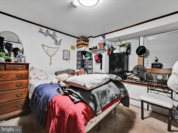 a bedroom with a bed a dresser and next to a window