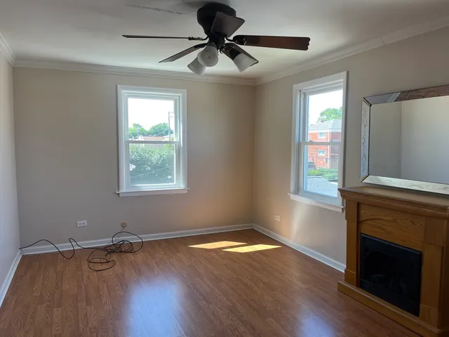 a view of hallway with wooden floor and fan
