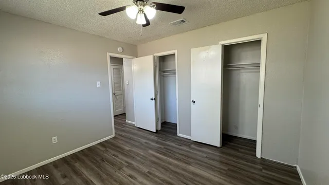an empty room with wooden floor and a ceiling fan