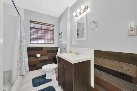 a bathroom with a sink a toilet a mirror and shower