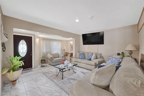 a living room with furniture a flat screen tv and a potted plant