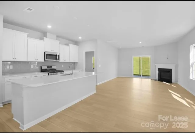 a view of kitchen with granite countertop a sink dishwasher stove top oven and cabinets with wooden floor