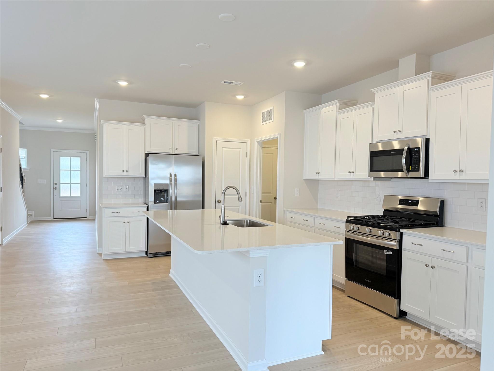 4326 Shimmering Stone Way Maiden, NC 28650 - Photo 7 of 27 a large kitchen with stainless steel appliances granite countertop a stove a sink a refrigerator and white cabinets with wooden floor