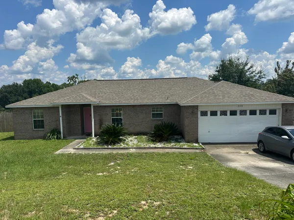 a front view of house with yard and trees in the background