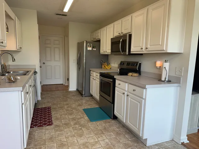 a kitchen with stainless steel appliances granite countertop a stove top oven a sink dishwasher and a refrigerator with wooden cabinets